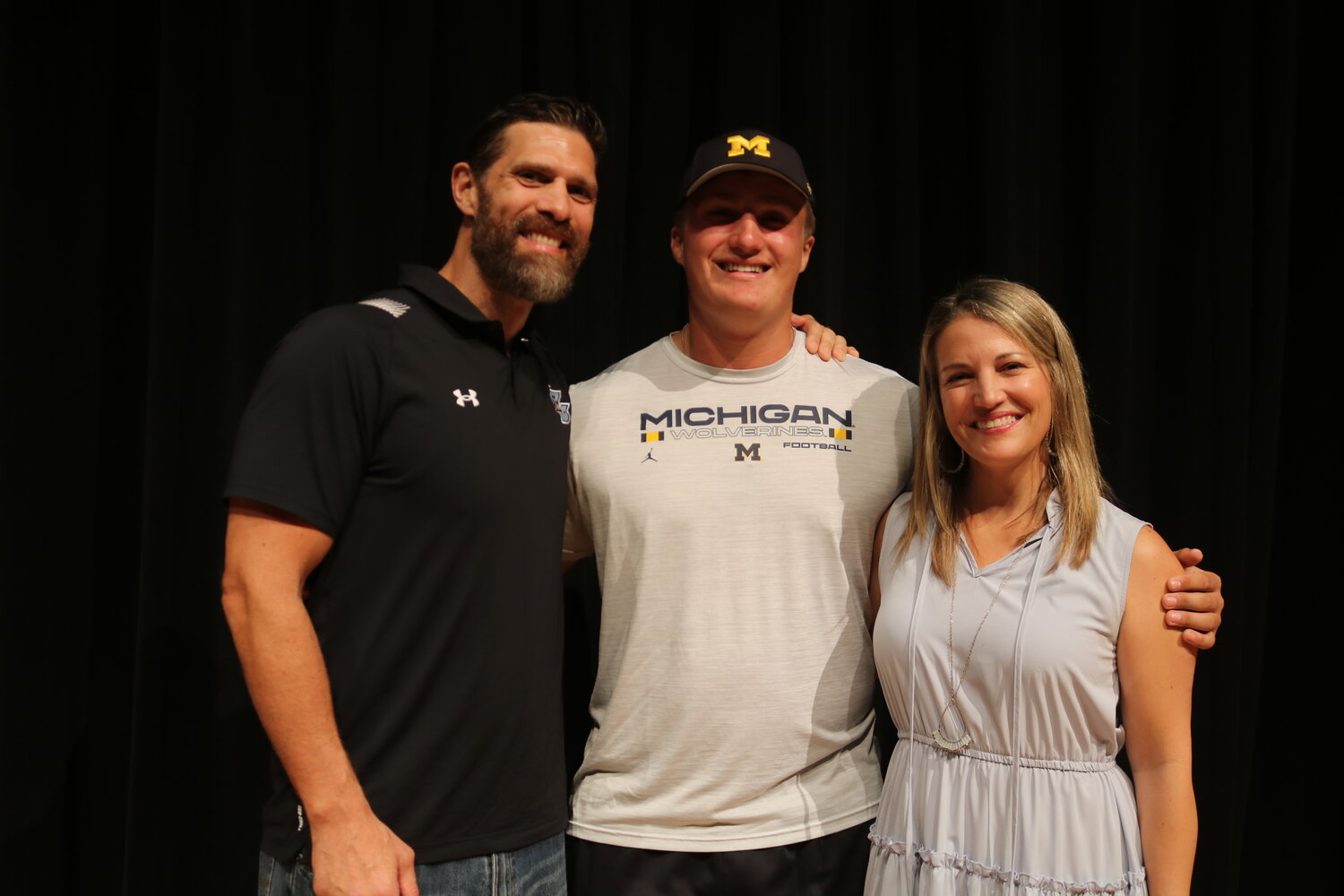 Jake Guarnera stands with his parents after committing to play football at the University of Michigan.